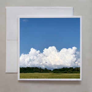 You can feel the approaching summer thunderstorm as big cumulonimbus clouds rise behind a forest in this photo greeting card by Caley Taylor.  